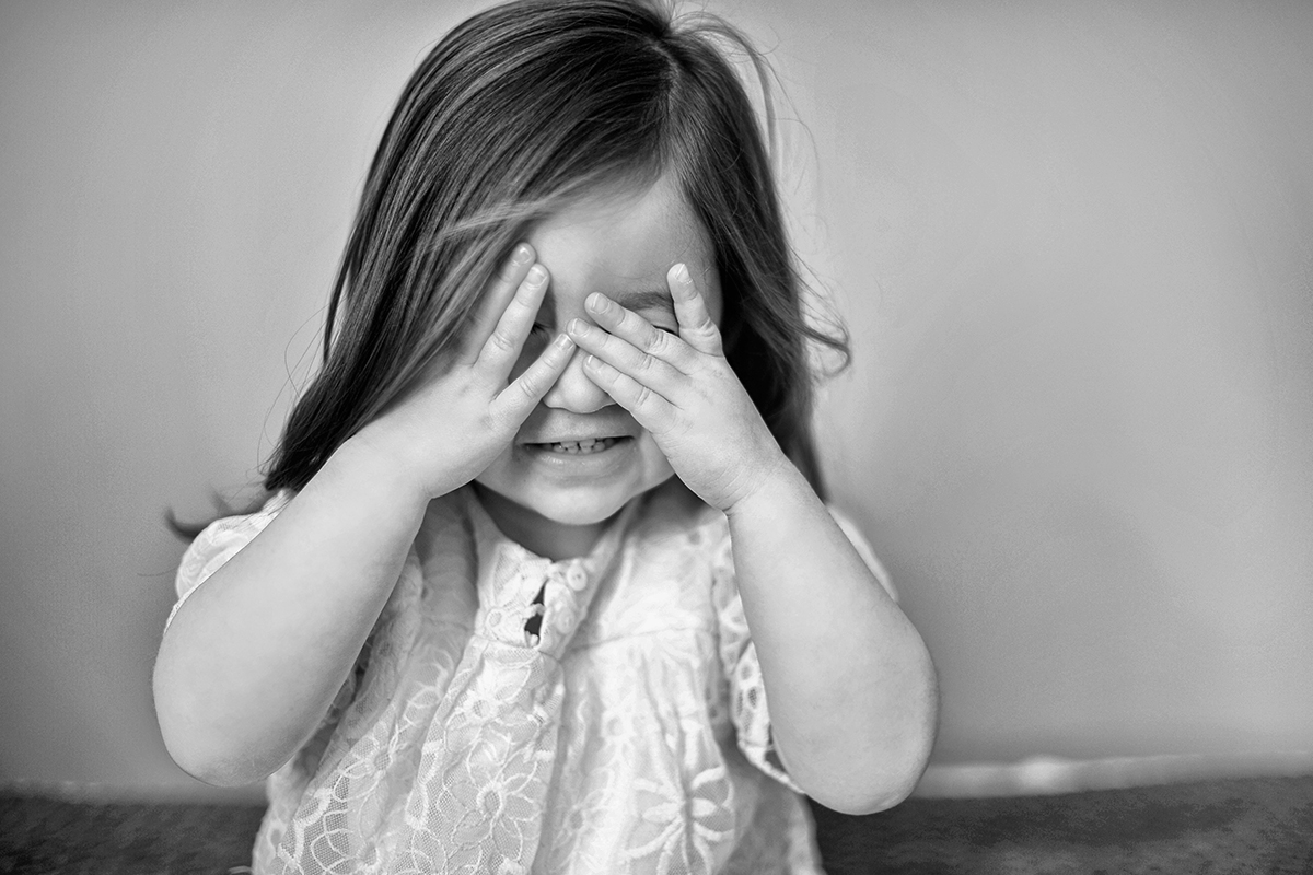 black and white photograph of a little girls hands holding on her face , filled with emotion